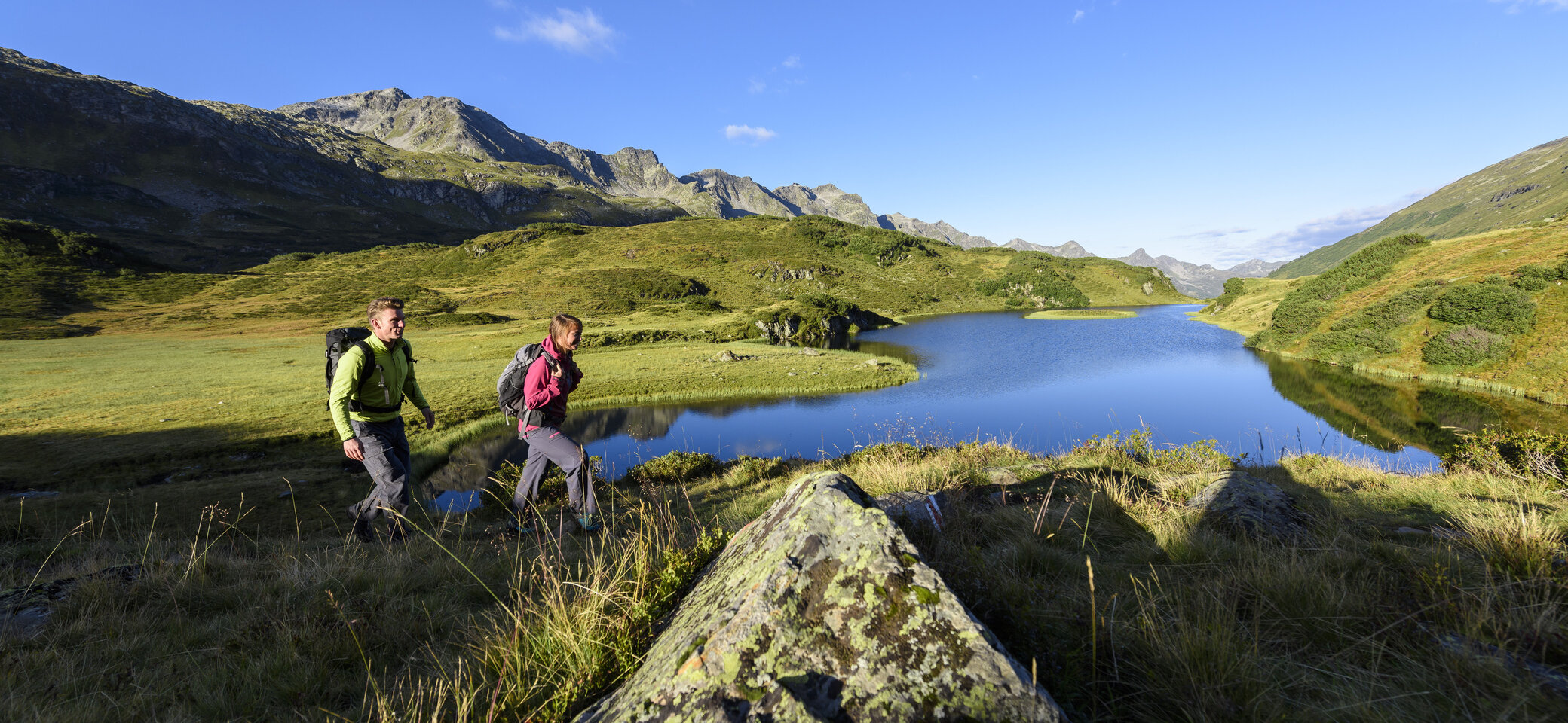 Wanderer im Frühling - im Hintergrund ein Bergsee | © DAV/Wolfgang Ehn